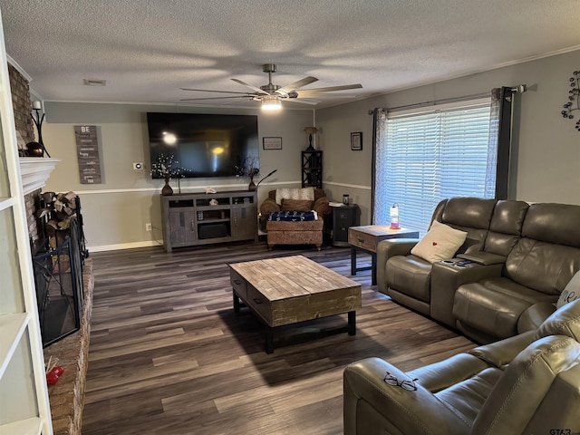 living room with a textured ceiling, ceiling fan, dark hardwood / wood-style flooring, and a fireplace