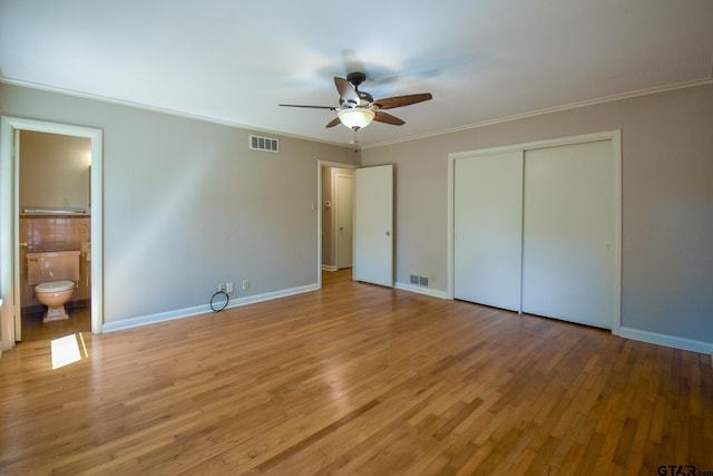 unfurnished bedroom featuring connected bathroom, a closet, ornamental molding, and light hardwood / wood-style floors