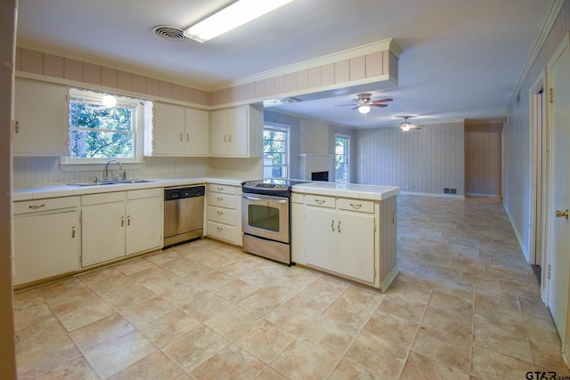 kitchen with stainless steel appliances, sink, crown molding, kitchen peninsula, and a healthy amount of sunlight