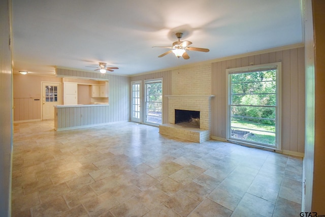 unfurnished living room featuring ceiling fan, ornamental molding, and a fireplace