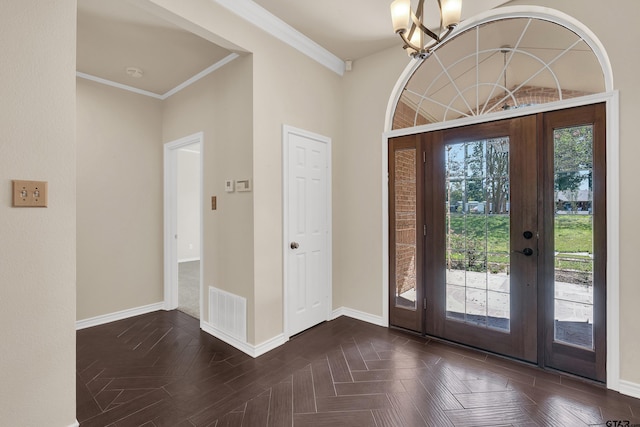 entrance foyer featuring ornamental molding, an inviting chandelier, and dark parquet flooring