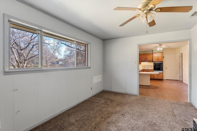 empty room featuring ceiling fan, light colored carpet, and ornamental molding