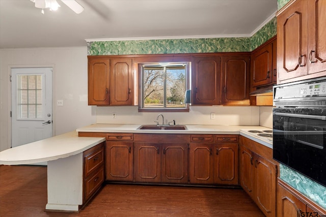 kitchen with kitchen peninsula, dark wood-type flooring, sink, and oven