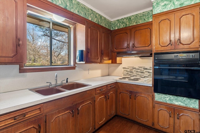 kitchen featuring dark wood-type flooring, sink, ornamental molding, white stovetop, and black oven