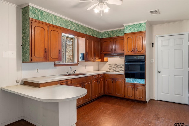 kitchen with sink, kitchen peninsula, oven, wood-type flooring, and crown molding