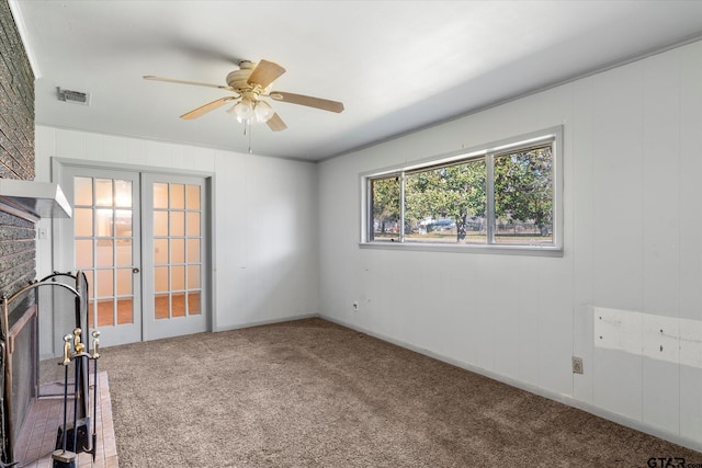 interior space featuring a brick fireplace, ceiling fan, and french doors