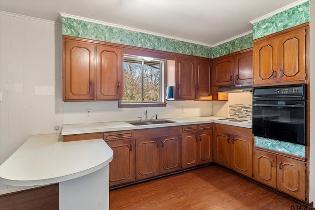 kitchen featuring oven, sink, crown molding, and wood-type flooring