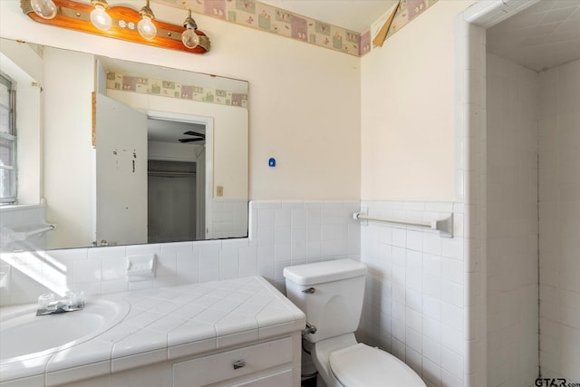 bathroom with vanity, toilet, and tile walls