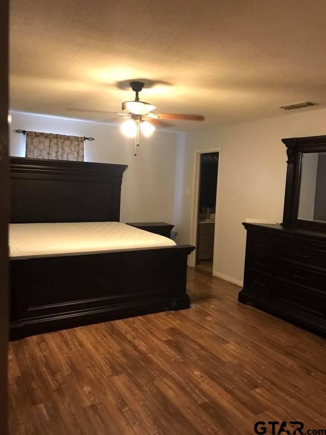 bedroom featuring ceiling fan, visible vents, baseboards, and wood finished floors