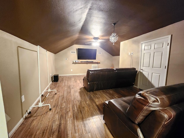 cinema with baseboards, a textured ceiling, lofted ceiling, and hardwood / wood-style flooring