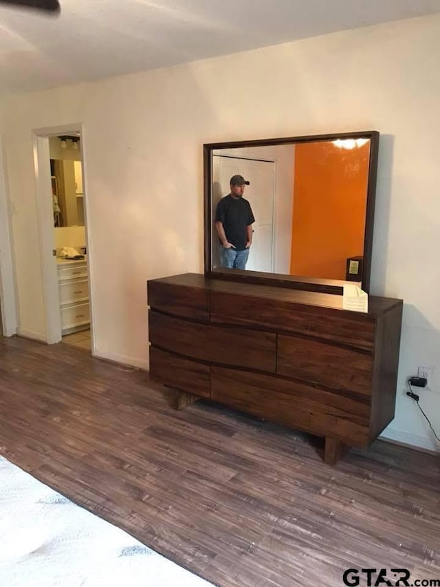 bedroom featuring ensuite bathroom, baseboards, and wood finished floors