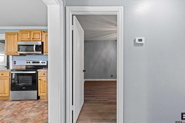 kitchen featuring light brown cabinets, light wood-type flooring, stainless steel appliances, and crown molding