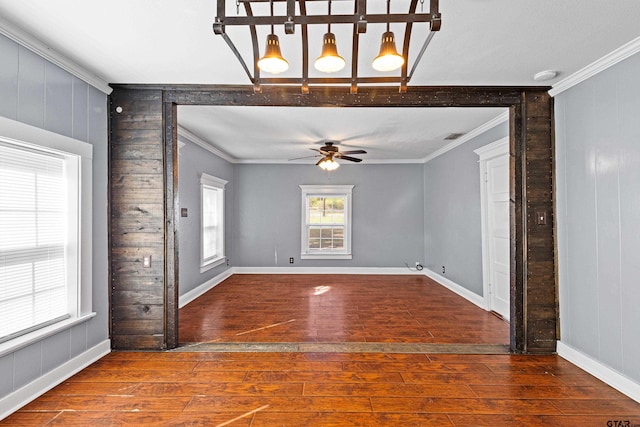 spare room featuring hardwood / wood-style flooring, ceiling fan, ornamental molding, and wood walls