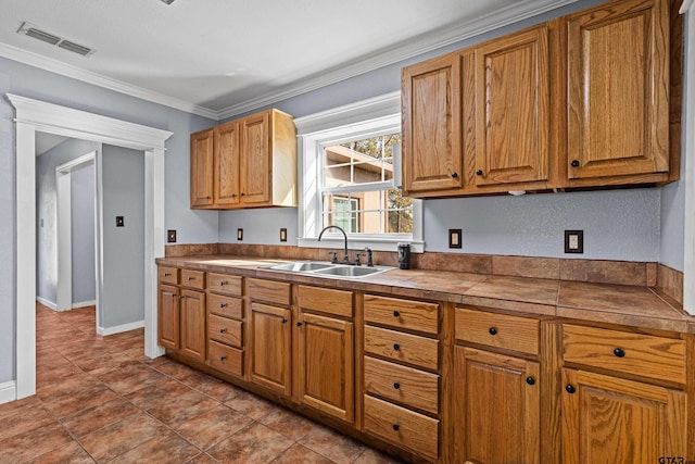 kitchen with tile countertops, sink, light tile patterned floors, and ornamental molding