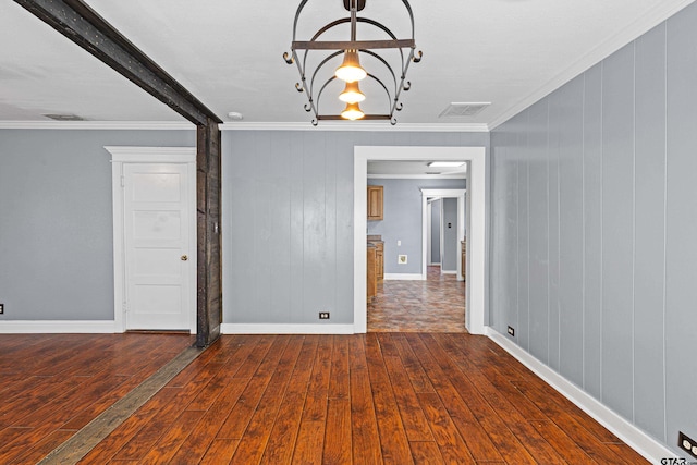 spare room with dark wood-type flooring, wooden walls, ornamental molding, beamed ceiling, and a notable chandelier