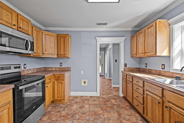 kitchen featuring light tile patterned floors, stainless steel appliances, ornamental molding, and sink