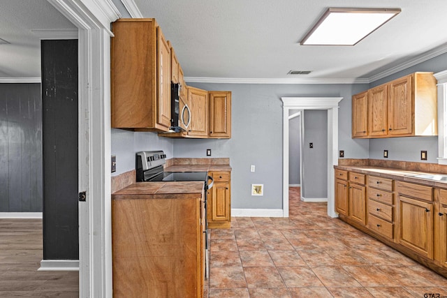 kitchen with stainless steel appliances, a textured ceiling, and ornamental molding