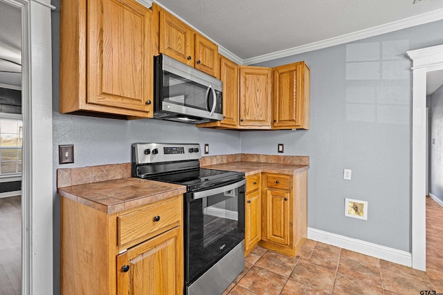 kitchen with light tile patterned floors, crown molding, and appliances with stainless steel finishes