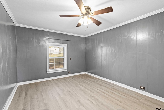 unfurnished room featuring ceiling fan, light hardwood / wood-style floors, ornamental molding, and wooden walls