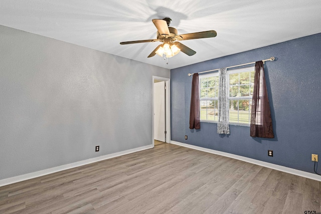 empty room with ceiling fan and light hardwood / wood-style flooring