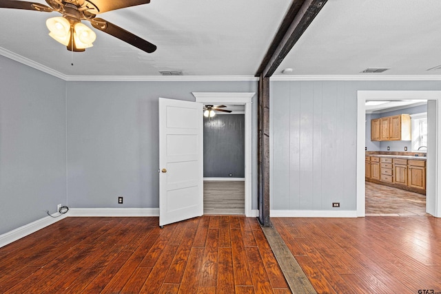 spare room featuring sink, dark hardwood / wood-style flooring, crown molding, and wooden walls