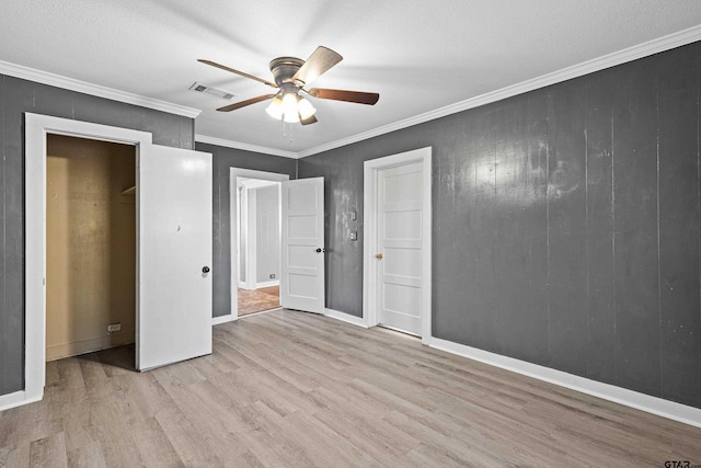 unfurnished bedroom featuring ceiling fan, crown molding, a textured ceiling, and light wood-type flooring