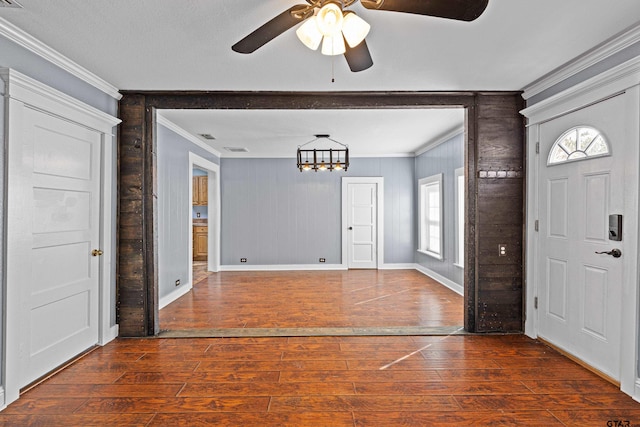 entryway featuring crown molding, wood walls, ceiling fan with notable chandelier, and dark hardwood / wood-style floors