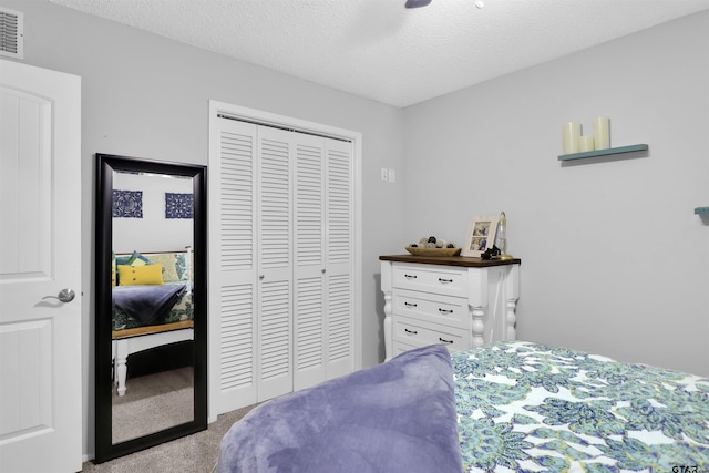 carpeted bedroom with a textured ceiling, ceiling fan, and a closet