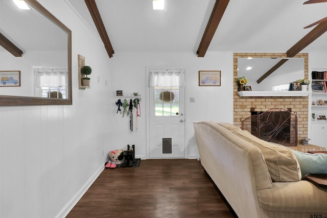 living room with beam ceiling, dark wood-type flooring, a brick fireplace, and plenty of natural light