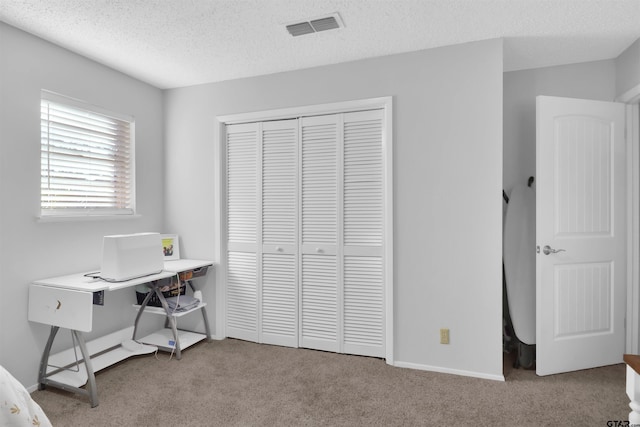 bedroom featuring a textured ceiling, light colored carpet, and a closet