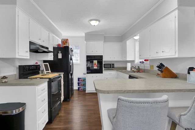 kitchen featuring kitchen peninsula, a breakfast bar, black appliances, white cabinets, and sink