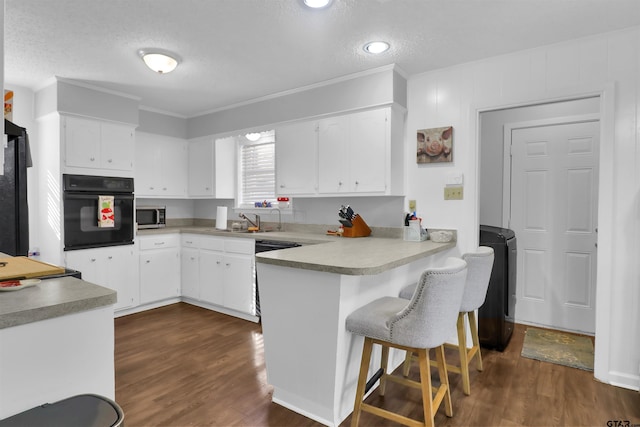 kitchen with a textured ceiling, white cabinetry, dark hardwood / wood-style flooring, and oven