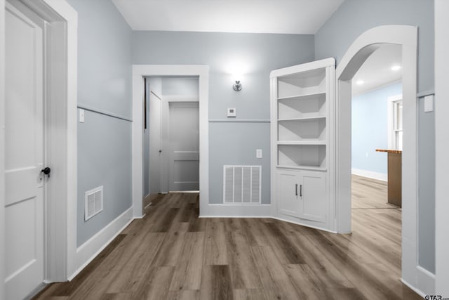 hall featuring arched walkways, wood finished floors, and visible vents