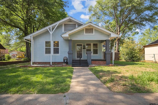 bungalow-style house featuring a front yard, covered porch, and fence