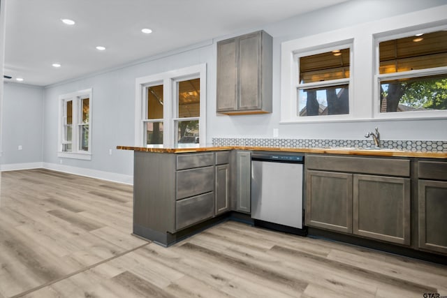 kitchen featuring a sink, dishwasher, light wood finished floors, baseboards, and a peninsula