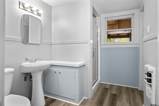 full bath featuring a sink, toilet, wood finished floors, and a stall shower