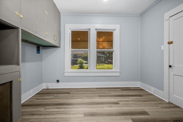 clothes washing area with cabinet space, wood finished floors, and baseboards