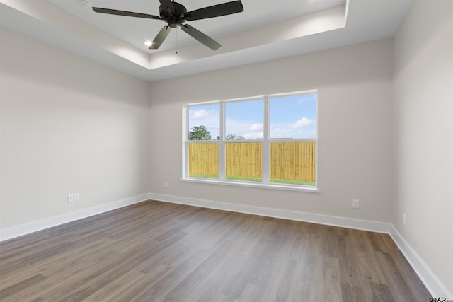 spare room with hardwood / wood-style floors, ceiling fan, and a tray ceiling