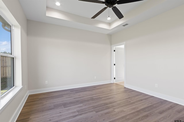 spare room featuring a tray ceiling, ceiling fan, and hardwood / wood-style flooring