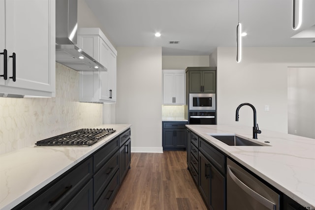 kitchen with white cabinetry, sink, wall chimney exhaust hood, stainless steel appliances, and decorative light fixtures