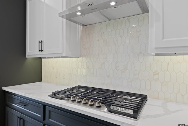 kitchen featuring white cabinets, light stone countertops, stainless steel gas stovetop, and exhaust hood