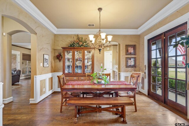 1299 Shadow Lks, Terrell, TX 75160 - dining space with arched walkways, wood finished floors, crown molding, a wainscoted wall, and a chandelier