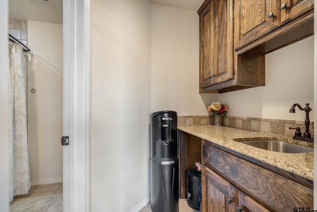 1299 Shadow Lks, Terrell, TX 75160 - kitchen featuring light stone counters, light tile patterned floors, and brown cabinetry