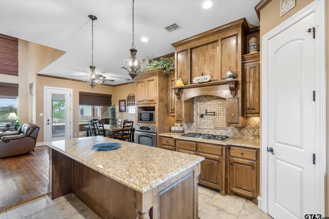 1299 Shadow Lks, Terrell, TX 75160 - kitchen with appliances with stainless steel finishes, ceiling fan, backsplash, a center island, and brown cabinets