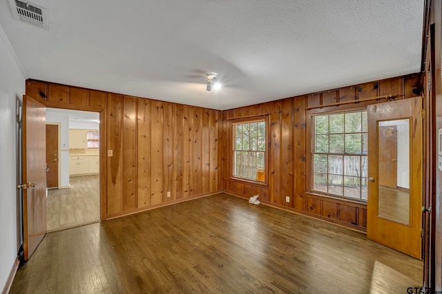 unfurnished room featuring hardwood / wood-style flooring and wooden walls