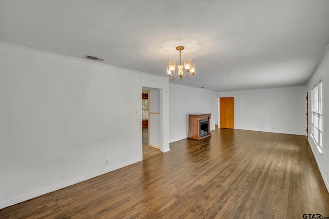 unfurnished living room featuring an inviting chandelier, dark hardwood / wood-style floors, and crown molding