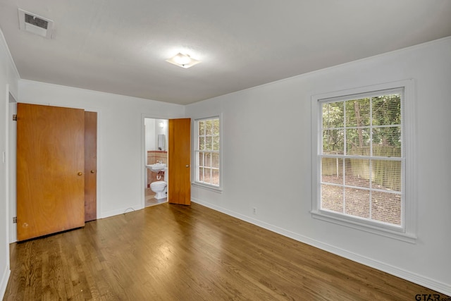 unfurnished bedroom with wood-type flooring and connected bathroom