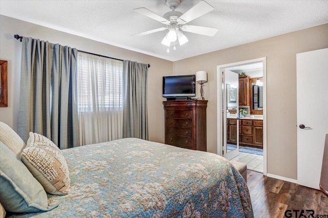 bedroom with ceiling fan, dark hardwood / wood-style floors, a textured ceiling, and connected bathroom