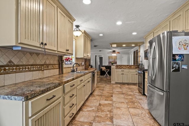 306 Dellwood Dr, Mount Pleasant, TX 75455 - kitchen with stainless steel appliances, cream cabinets, tasteful backsplash, a peninsula, and recessed lighting