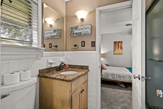 306 Dellwood Dr, Mount Pleasant, TX 75455 - ensuite bathroom with vanity, tile walls, and a wainscoted wall